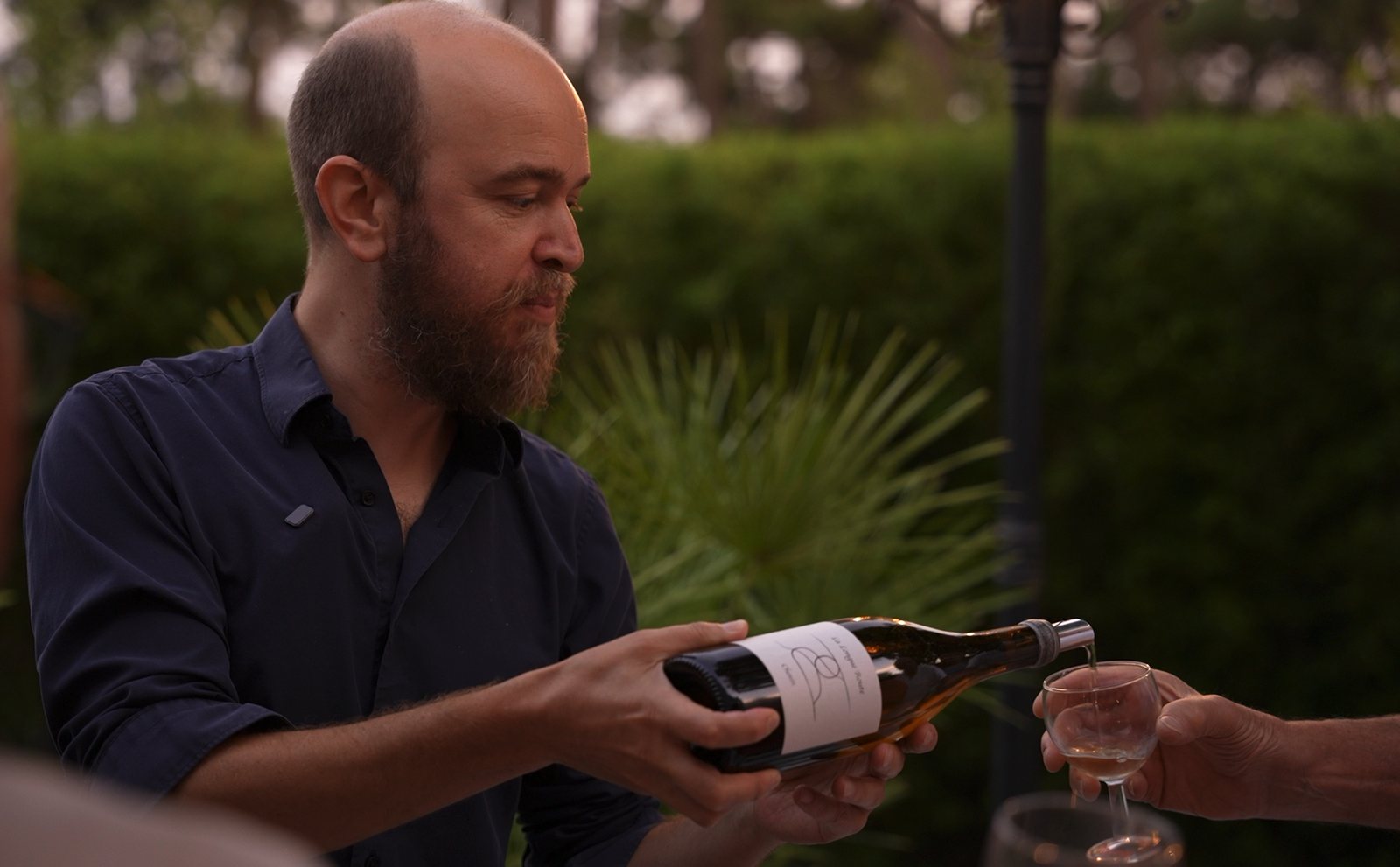 Augustin d'Assignies servant un verre de vin en extérieur, à Vannes
